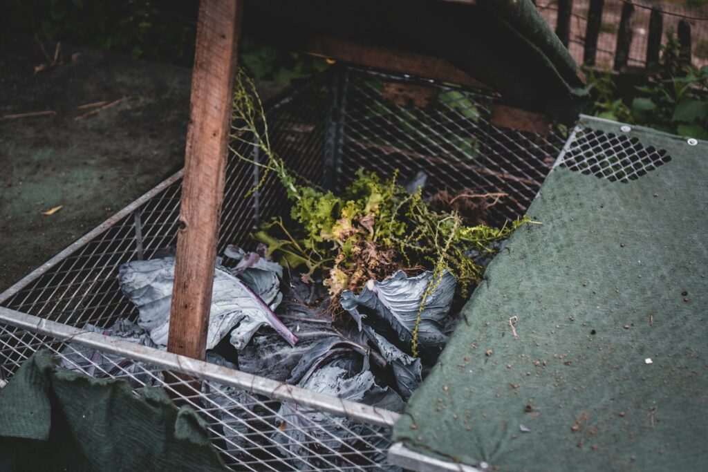 Compostera de madera con restos vegetales en un patio