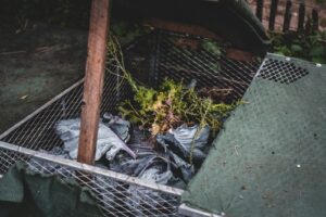 Compostera de madera con restos vegetales en un patio